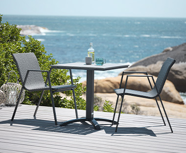 Dvije stolice i stol na terasi uz more