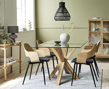 Stakleni stol s modernim stolicama u kombinaciji crne boje i drva