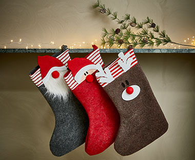 Tri božićne čarape obješene kraj lampica