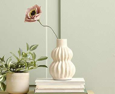 Vaza i umjetni cvijet na knjigama