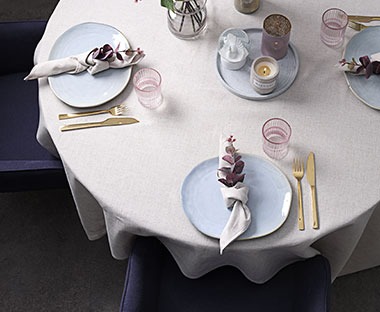 Postavljen stol s bijelim tanjurima i zlatnim žlicama i noževima