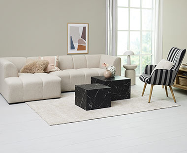 Bijela moderna sofa s prugastom foteljom i crnim stolićima