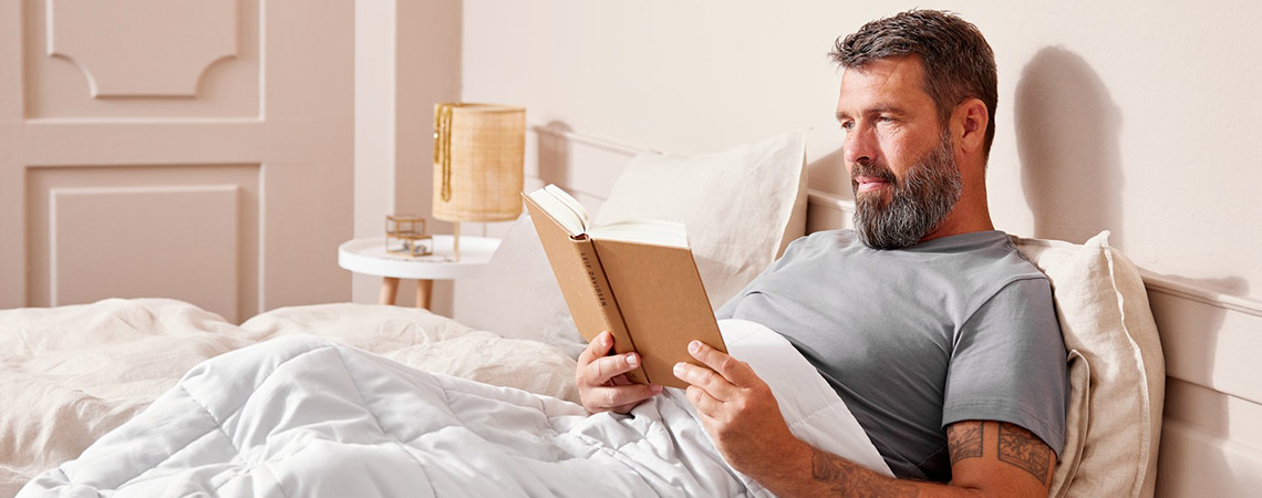 Muškarac čita knjigu u krevetu