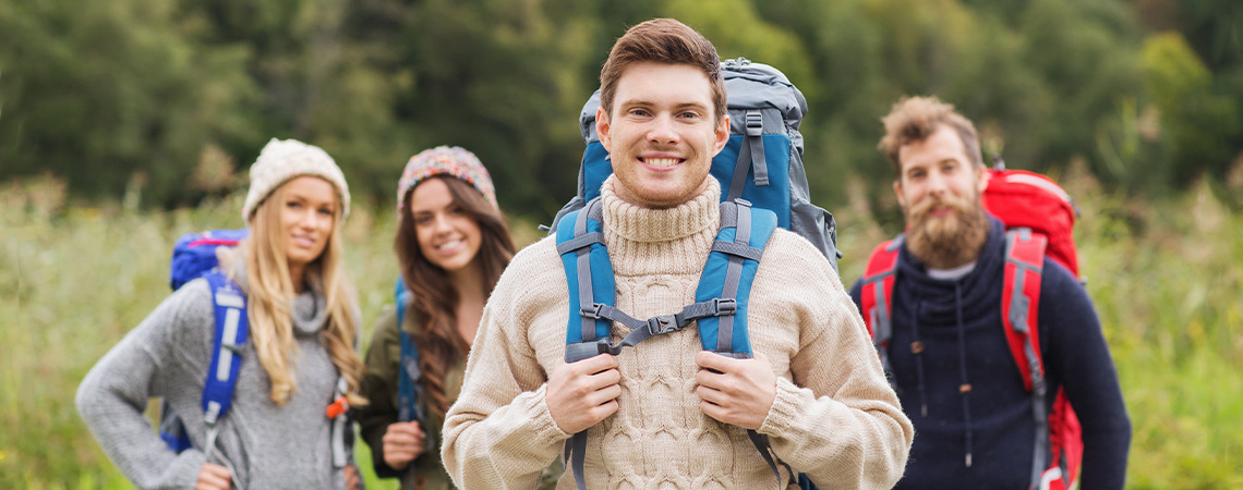 Nasmiješena skupina putnika s ruksakom koji planinare šumovitim područjem