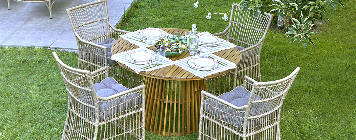 Okrugli vrtni stol i četiri vrtne stolice na travnjaku