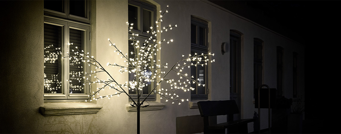 LED svjetleće drvce ispred kuće u mraku 