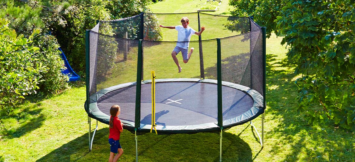 Djeca se igraju na velikom trampolinu u vrtu
