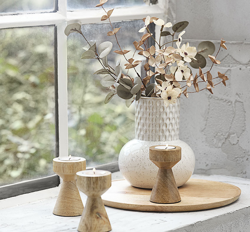 Svjetlo-bež ili bijela reljefna vaza s umjetnim cvijećem i drvenim držačima za lučice