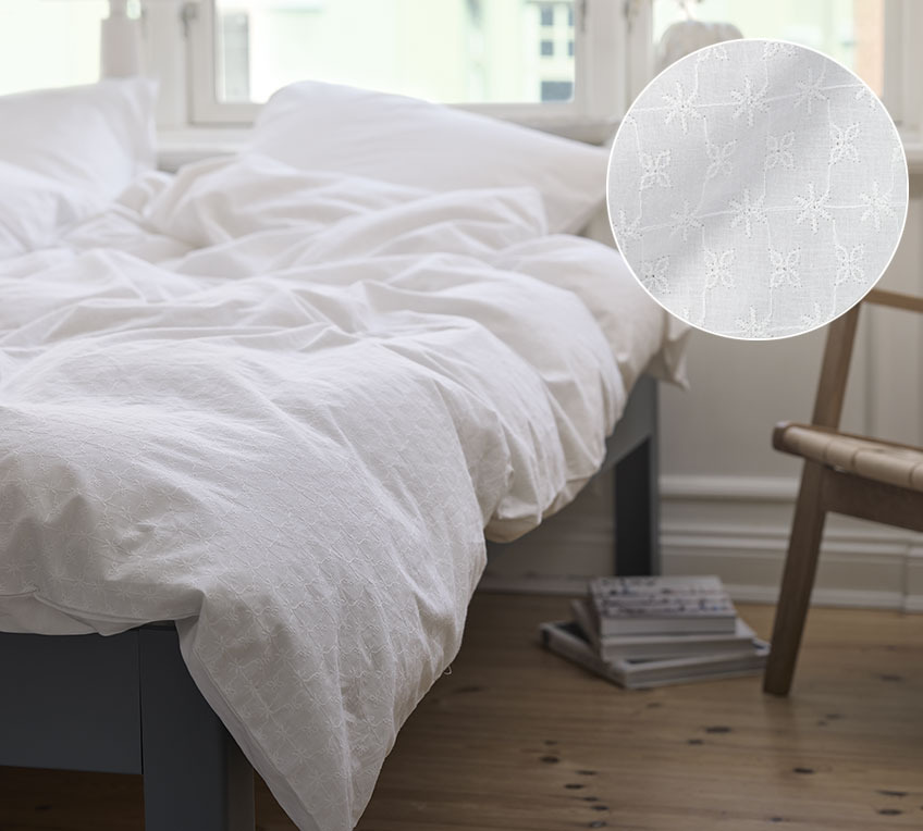 Bijela posteljina u svijetloj spavaćoj sobi s vezenim uzorkom