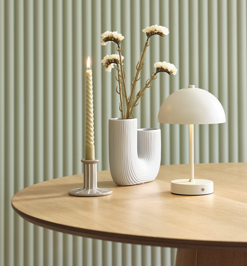 Elegantna lampa na baterije s mesinganim detaljem, vaza i svijećnjak na drvenom stolu