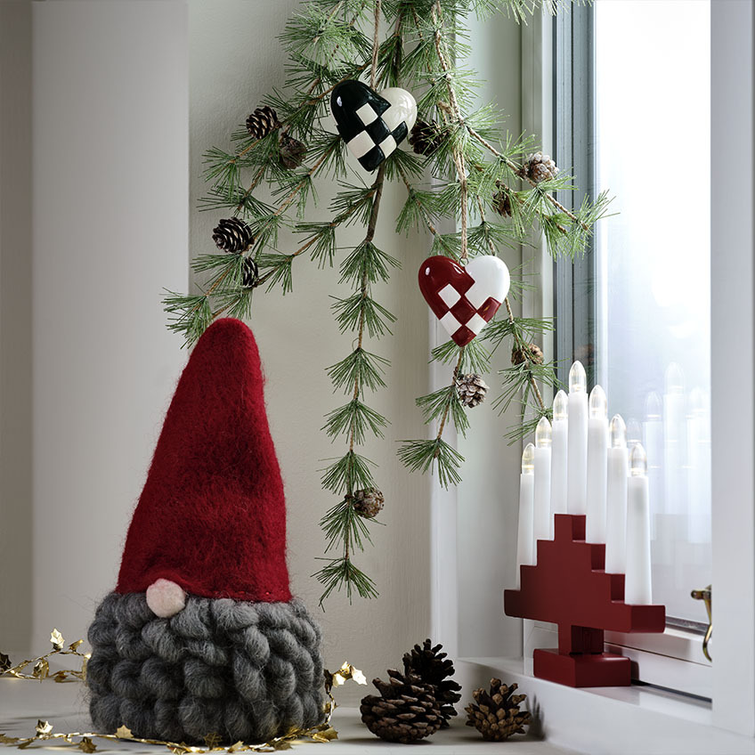 Skandinavski božićni gnom sa sijedom bradom na ukrašenoj prozorskoj dasci 