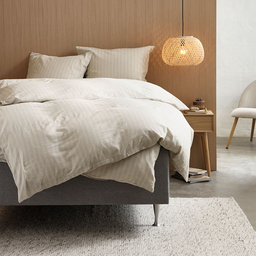 Set posteljine od pamučnog flanela u toploj bež boji sa prugastim dizajnom na krevetu u spavaćoj sobi