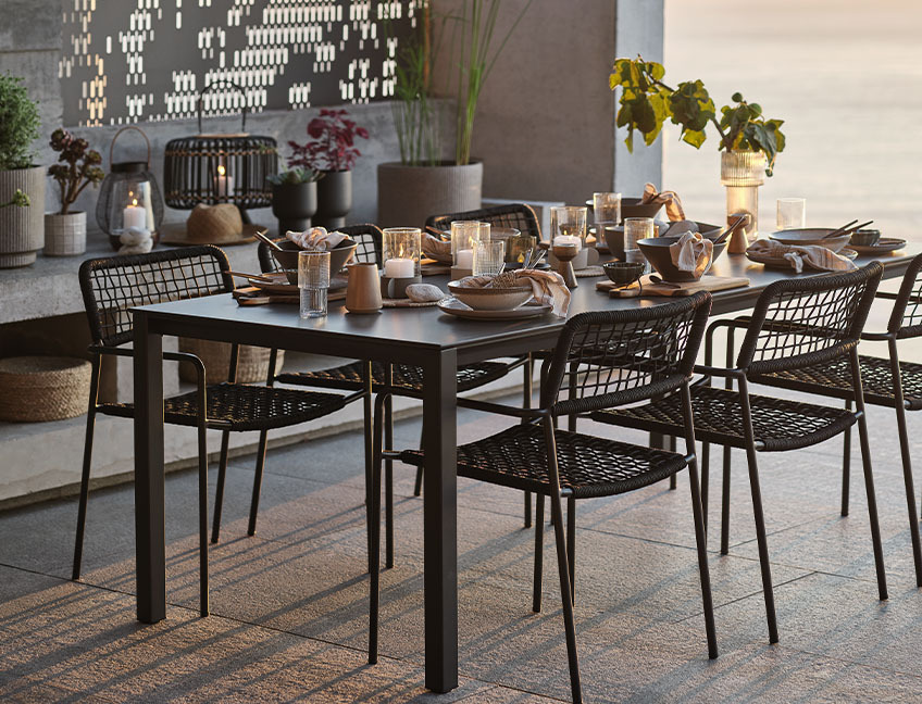 Vrtni stol i vrtne stolice s postavljenim stolom za večeru na terasi uz zalazak sunca