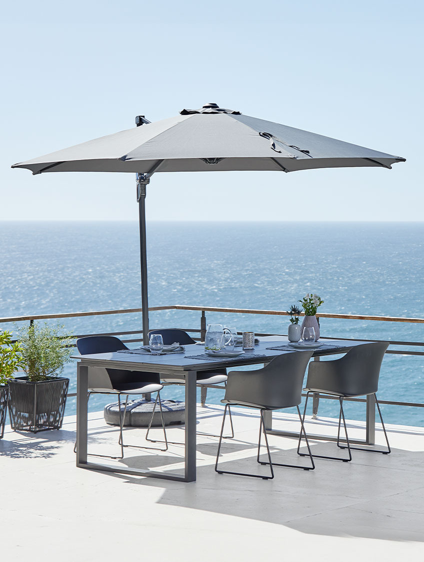 Veliki viseći suncobran i vrtni stol i stolice na terasi uz ocean