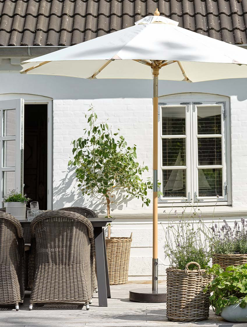Klasični prljavo bijeli vrtni suncobran na terasi s vrtnim stolom i vrtnim stolicama