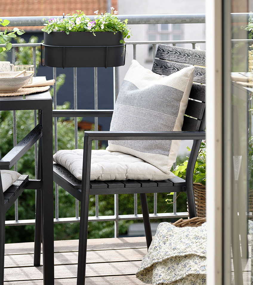 Crna vrtna stolica koja se slaže s jastucima na balkonu