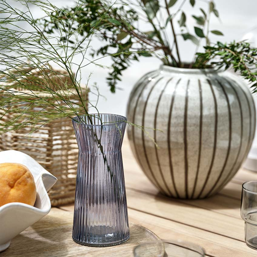 Vaze, lampion i zdjela na drvenom vrtnom stolu na otvorenom 