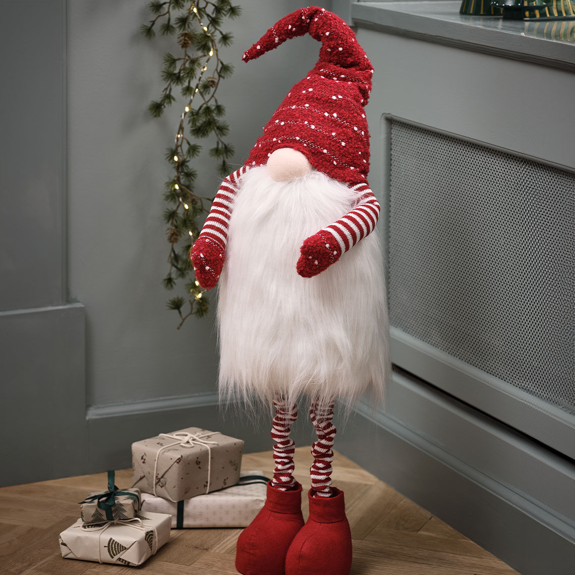 Božićni patuljak NAT kraj poklona Visoki božićni patuljak s crvenim šeširom i velikom bradom pored poklona