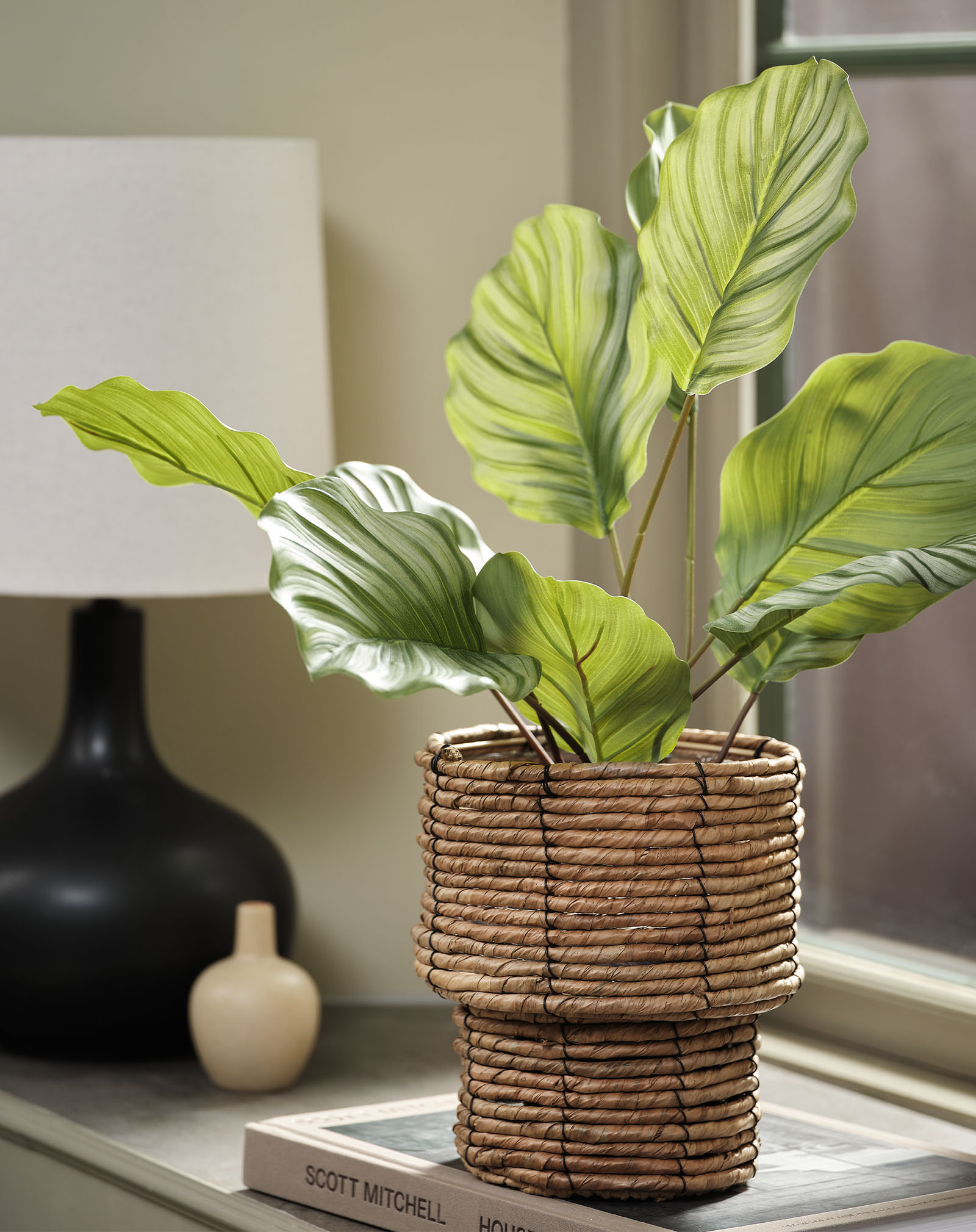Artificial plant imitation of a calathea plant in a woven plant pot  