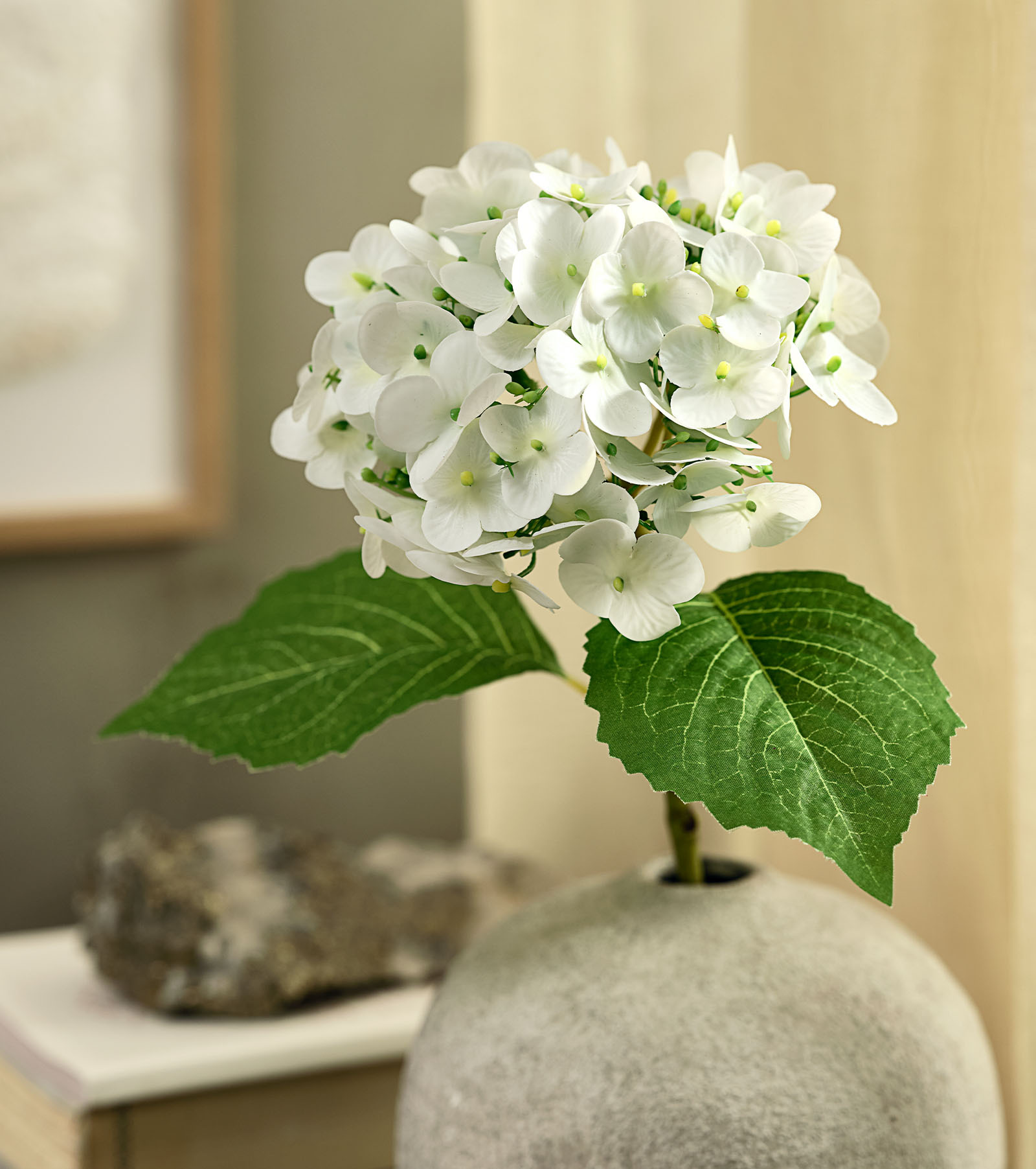 Artificial flower imitation of a white hydrangea with green leaves in a rustic vase 