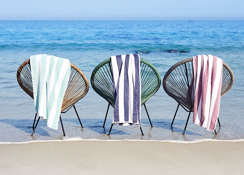Lounge vrtne stolice na plaži s velikim ručnicima za plažu prebačenim preko naslona za leđa