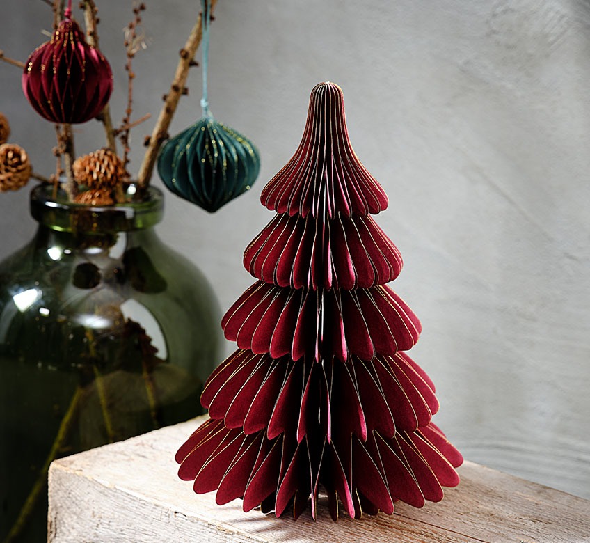 Velika staklena vaza i malo tamno crveno božićno drvce od papira