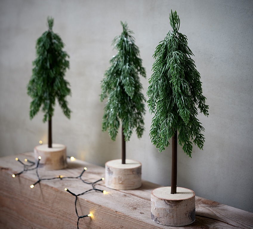 Tri umjetna bora na malom postolju od drveta predstavljaju moredni božićni ukras.