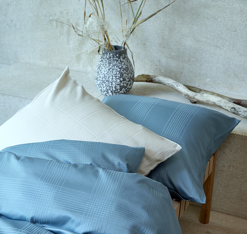 Jastuk i poplun u luksuznoj posteljini petrol plave i boje pjeska
