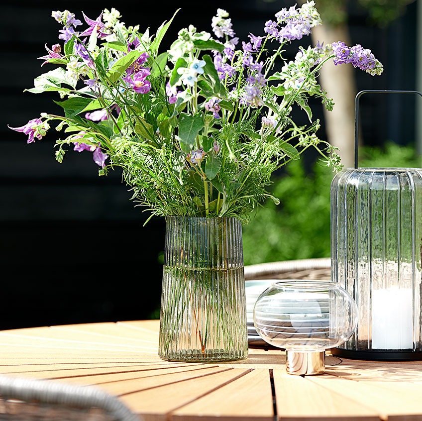 Staklena vaza i fenjeri na okruglom vrtnom stolu