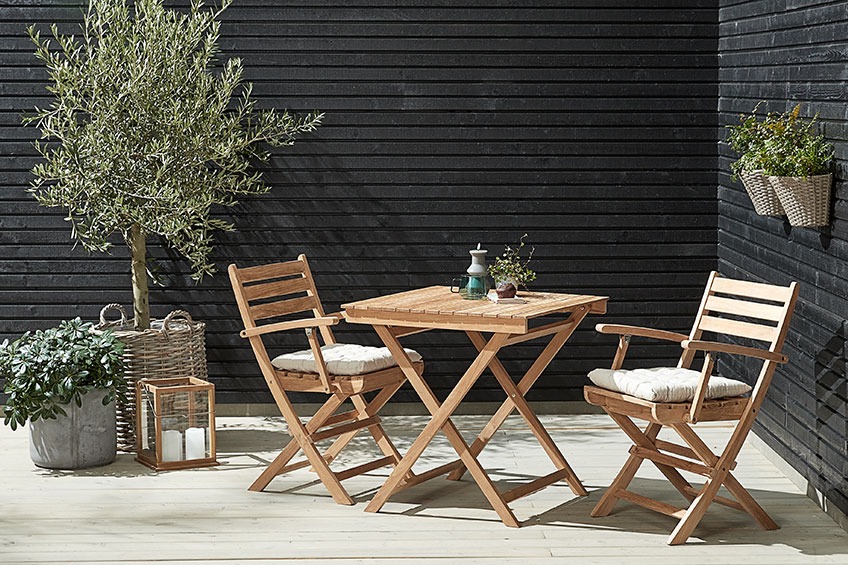 Bistro set VESTERHAVET s malim stolom i dvije sklopive stolice Bistro set s malim stolom i dvije sklopive stolice u kutu na terasi