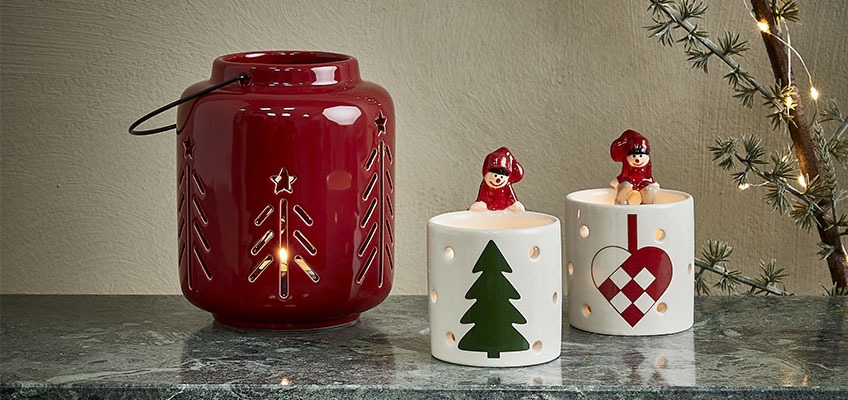 Božićni fenjer crvene boje i svijećnjaci s božićnim motivima