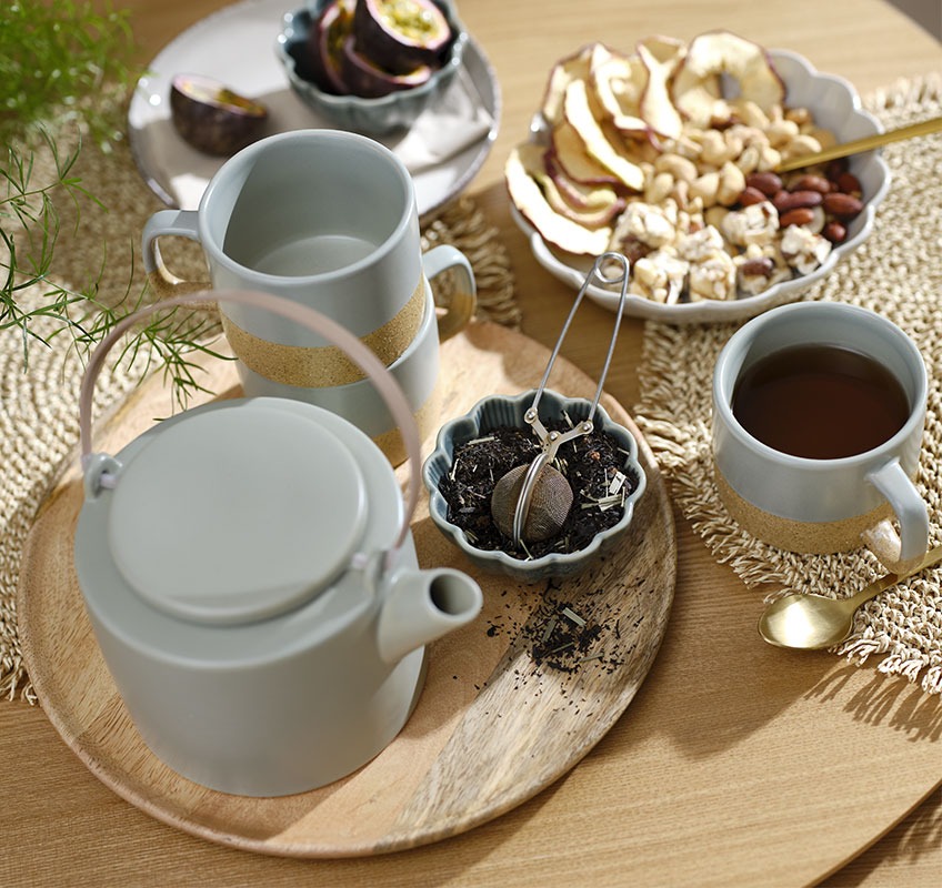 Drveni pladanj sa zelenim čajnikom i šalicama i malim zdjelicama s grickalicama i čajem