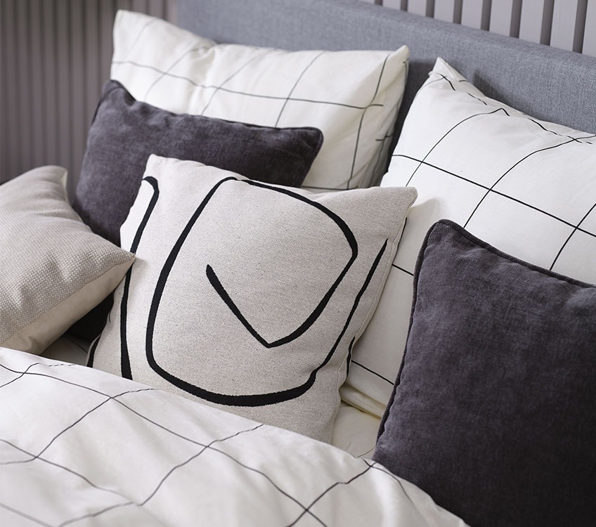 Bedroom with white and black bed linen and black and with decorative cushions  