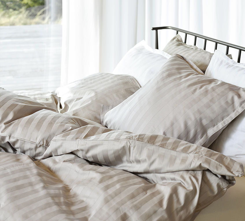 Krevet s poplunima i jastucima s prugastom posteljinom