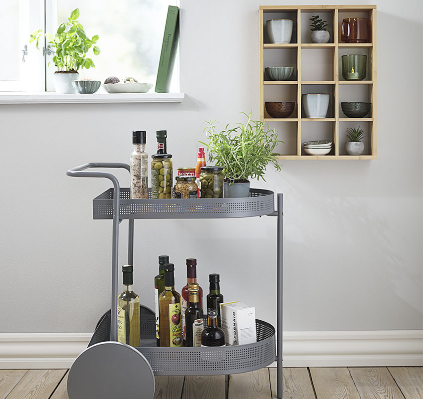 Siva kolica s kuhinjskim elementima i zidnom policom na kojoj su izložene šalice i zdjelice
