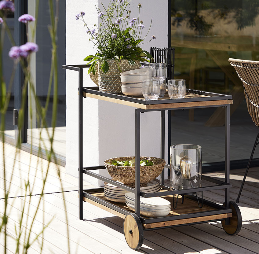 UGILT trolley, NICOLAI storage box and KNUT decorative bowl Trolley with plates and glasses on a patio