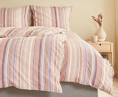 Šarena posteljina na pruge na krevetu u sobi
