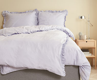Romantična posteljina u pastelnoj ljubičastoj boji na krevetu u sobi