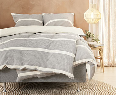 Sivo-bijela posteljina na pruge na dvostrukom krevetu
