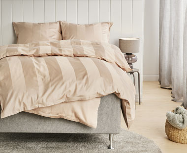 Satenska posteljina u bež boji na krevetu