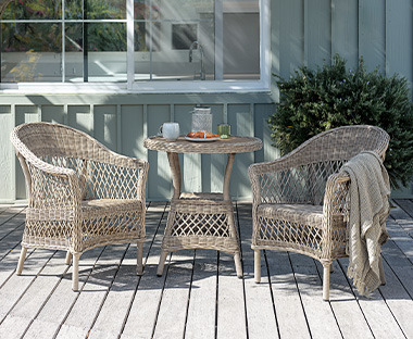 Pleteni okrugli stol i pletene stolice u sjeni na terasi