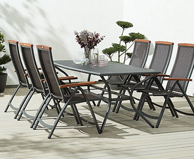 Veliki metalni stol i 6 stolica s drvenim rukohvatima na terasi